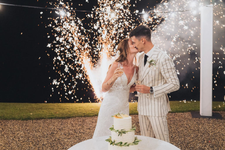 Couple découpant le gâteau de mariage avec des étincelles